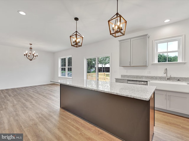 kitchen featuring a center island, decorative light fixtures, sink, and light wood-type flooring