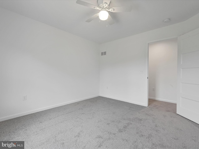 spare room featuring dark carpet and ceiling fan