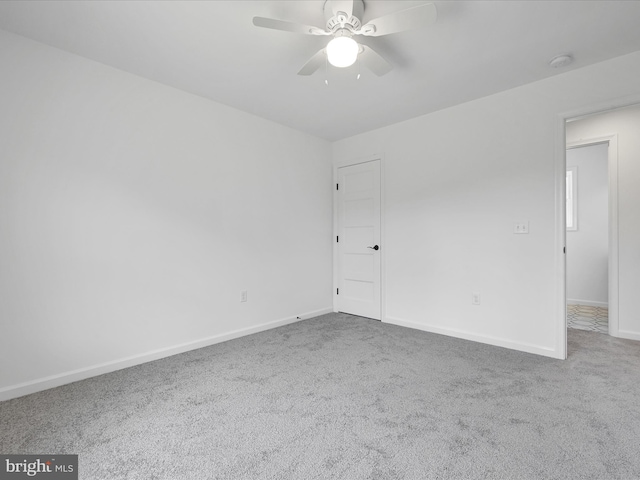 spare room with dark carpet and ceiling fan