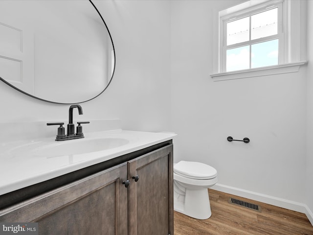 bathroom with hardwood / wood-style floors, vanity with extensive cabinet space, and toilet