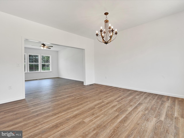 unfurnished room with ceiling fan with notable chandelier and hardwood / wood-style flooring