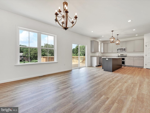 kitchen featuring hanging light fixtures, a healthy amount of sunlight, light wood-type flooring, stainless steel appliances, and a kitchen island