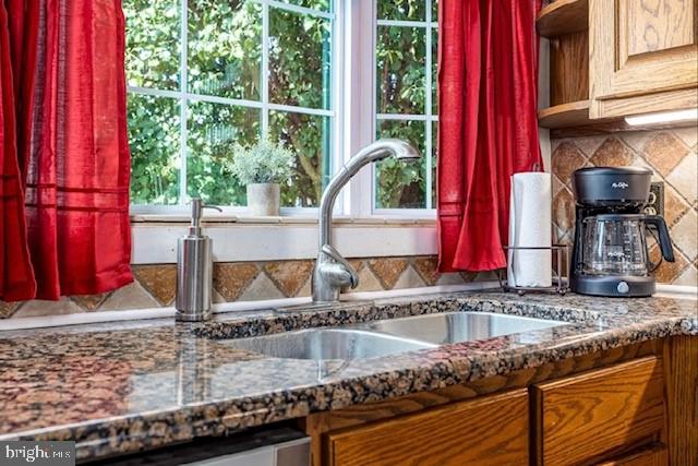 kitchen featuring plenty of natural light, tasteful backsplash, dark stone countertops, and sink