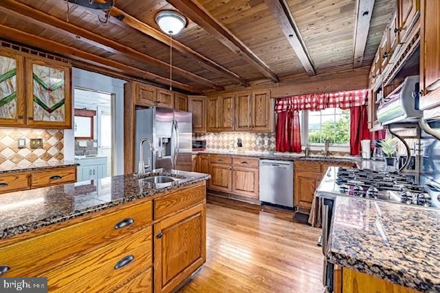 kitchen featuring tasteful backsplash, stainless steel appliances, dark stone countertops, sink, and wood ceiling