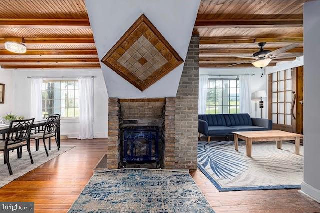 sitting room with brick wall, beamed ceiling, a fireplace, and dark hardwood / wood-style flooring