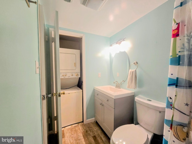 bathroom featuring oversized vanity, toilet, stacked washer / drying machine, and hardwood / wood-style flooring