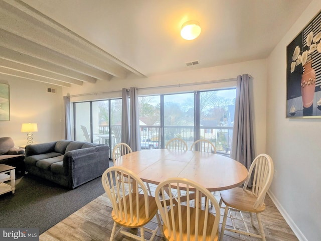 dining space featuring light hardwood / wood-style floors and beamed ceiling