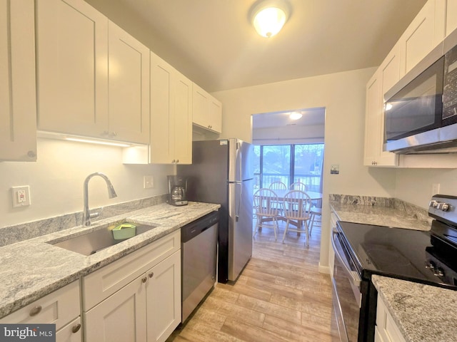 kitchen featuring appliances with stainless steel finishes, sink, light wood-type flooring, and white cabinets