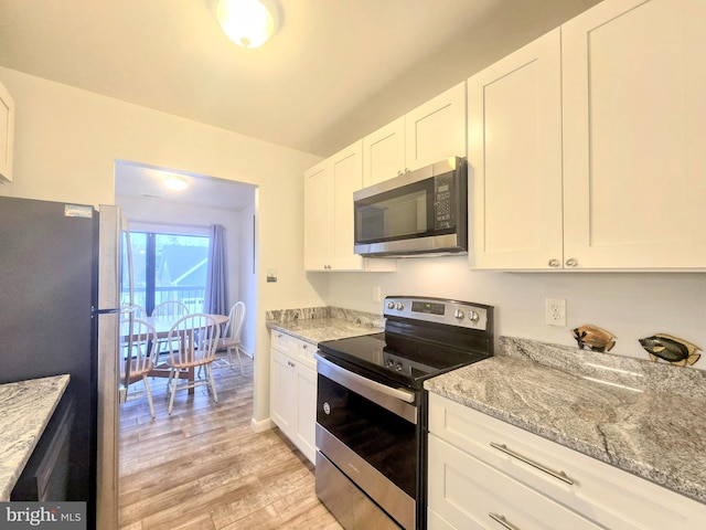 kitchen with light stone counters, stainless steel appliances, white cabinetry, and light hardwood / wood-style flooring