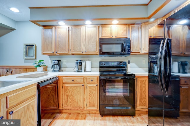 kitchen with light hardwood / wood-style flooring and black appliances