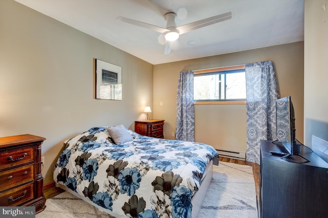 bedroom with ceiling fan, a baseboard heating unit, and light hardwood / wood-style flooring