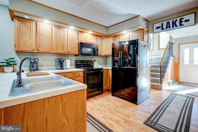 kitchen featuring sink, light wood-type flooring, and black appliances