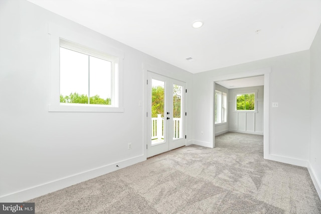 carpeted spare room featuring french doors