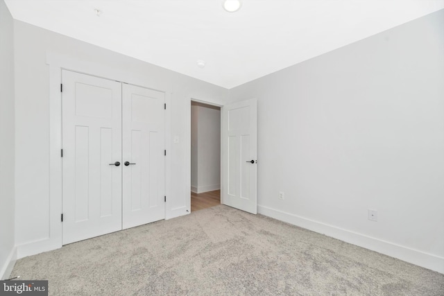 unfurnished bedroom with a closet and light colored carpet