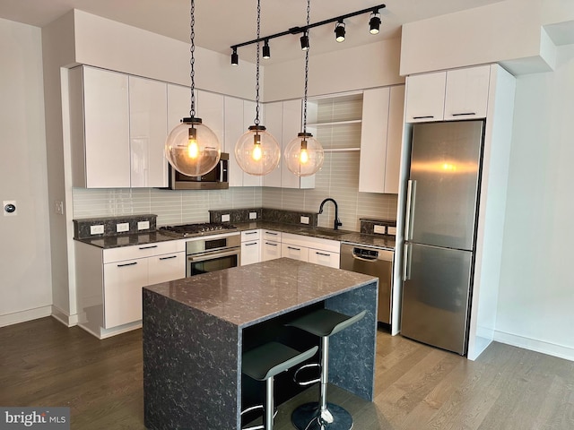 kitchen with pendant lighting, dark stone countertops, a breakfast bar area, stainless steel appliances, and tasteful backsplash