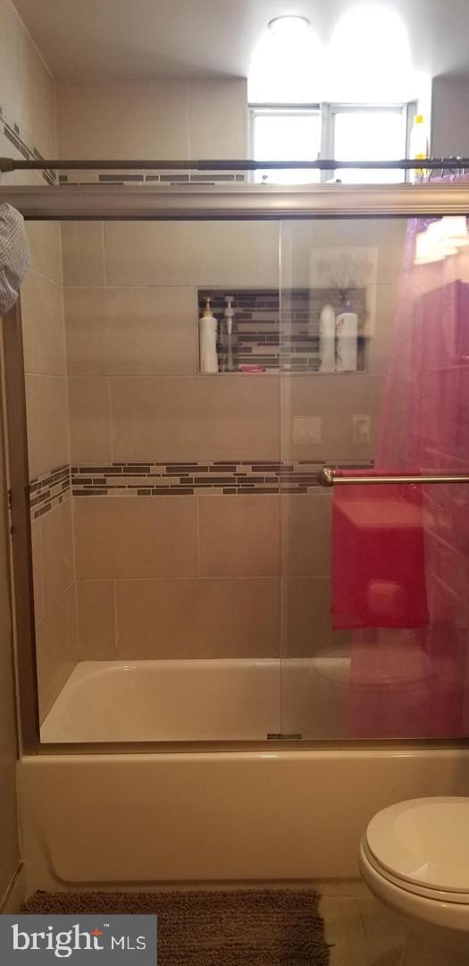 bathroom with toilet, combined bath / shower with glass door, and tile floors