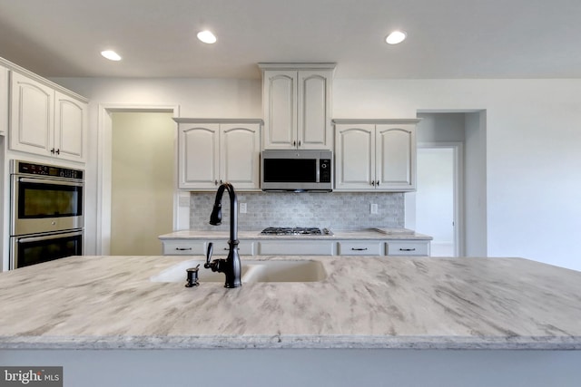 kitchen featuring appliances with stainless steel finishes, light stone counters, and white cabinetry