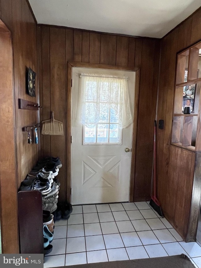 doorway with wood walls and light tile flooring