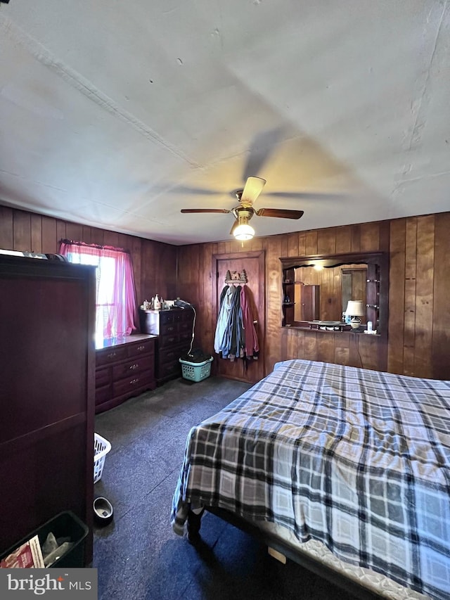 carpeted bedroom featuring wooden walls and ceiling fan