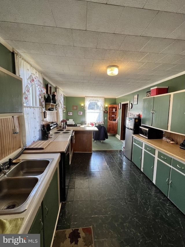 kitchen featuring stainless steel fridge, dark tile floors, green cabinetry, and sink