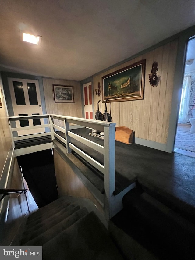 staircase featuring wood walls