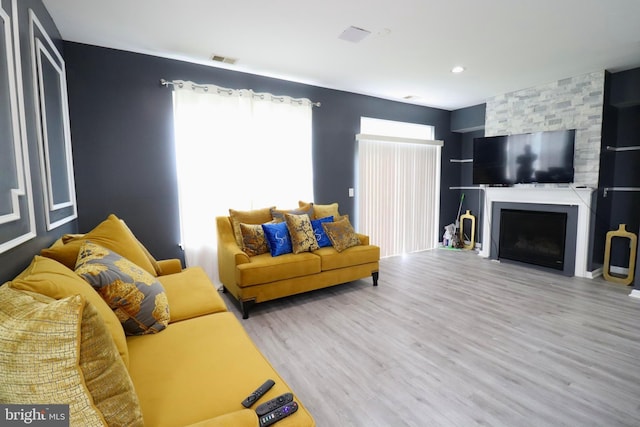 living area with visible vents, wood finished floors, and a fireplace