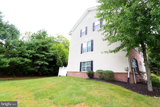 view of side of property featuring brick siding and a yard