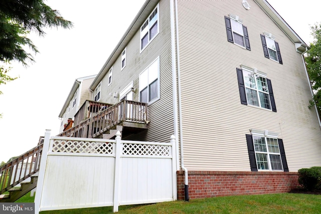 view of side of property featuring brick siding, stairway, and fence