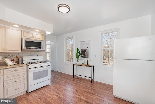 kitchen with backsplash, light hardwood / wood-style floors, white appliances, and a wealth of natural light