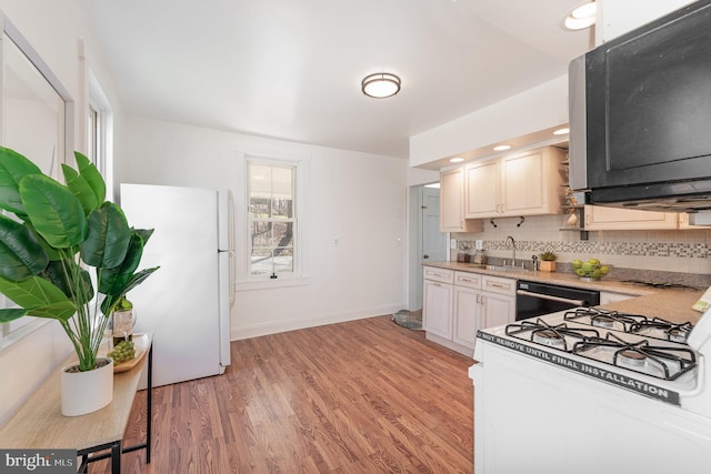 kitchen with sink, white refrigerator, dishwashing machine, backsplash, and light hardwood / wood-style floors