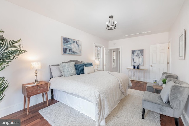 bedroom with hardwood / wood-style floors and an inviting chandelier