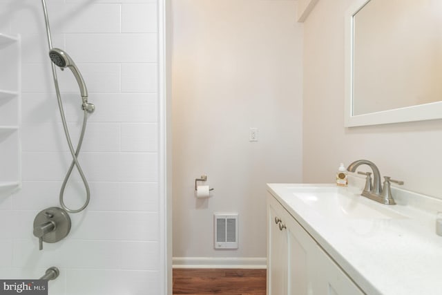 bathroom with tiled shower / bath combo, vanity with extensive cabinet space, and hardwood / wood-style flooring