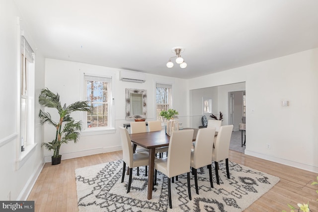 dining room featuring a notable chandelier, light hardwood / wood-style flooring, and a wall unit AC