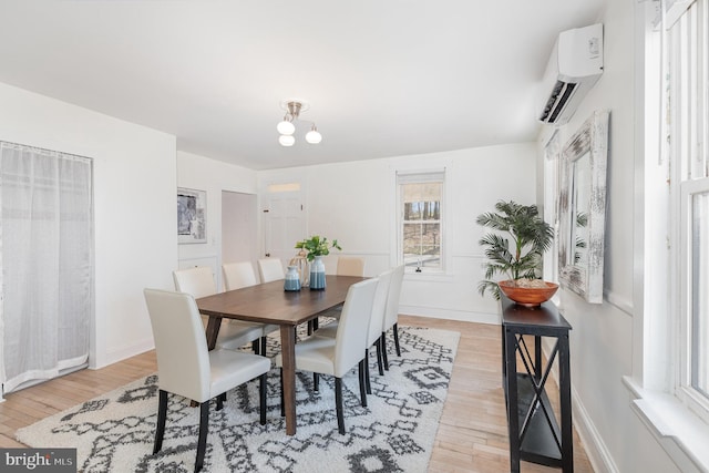 dining space featuring an inviting chandelier, an AC wall unit, and light hardwood / wood-style flooring