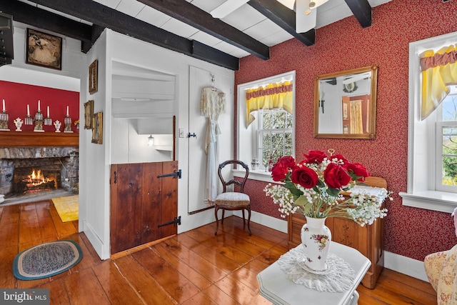 sitting room with hardwood / wood-style flooring, beam ceiling, a healthy amount of sunlight, and a fireplace