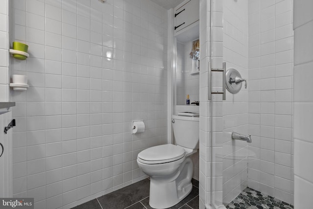 bathroom featuring tile walls, tile floors, toilet, and a tile shower