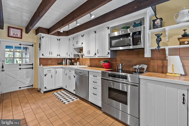 kitchen featuring appliances with stainless steel finishes, tasteful backsplash, beam ceiling, sink, and white cabinetry