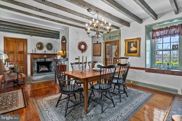 dining space featuring a high end fireplace, beamed ceiling, and a chandelier