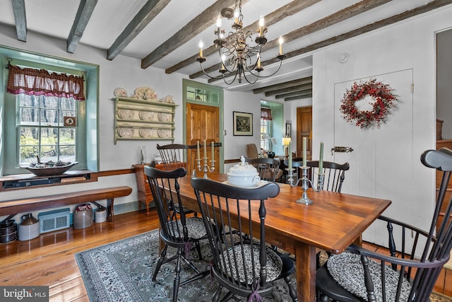 dining space featuring a chandelier, beam ceiling, and hardwood / wood-style flooring