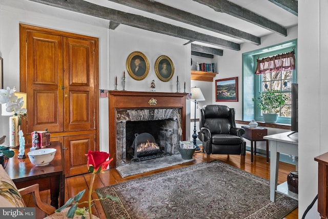 living room featuring beam ceiling, a fireplace, and wood-type flooring