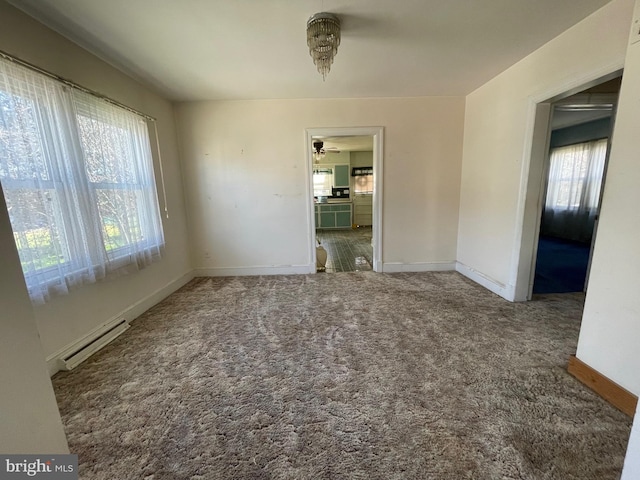 carpeted spare room with ceiling fan, baseboard heating, and a healthy amount of sunlight