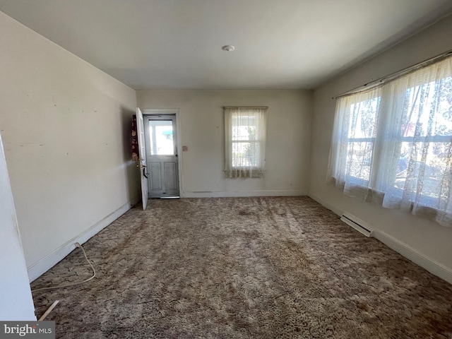 carpeted empty room featuring baseboard heating