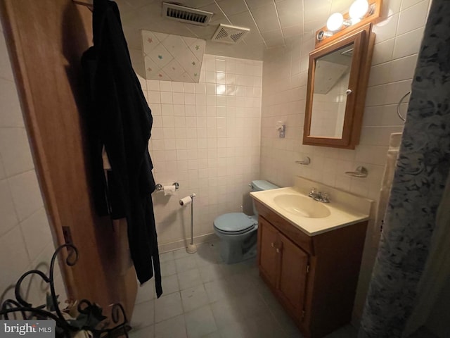 bathroom featuring tile walls, vanity, toilet, and tile patterned floors