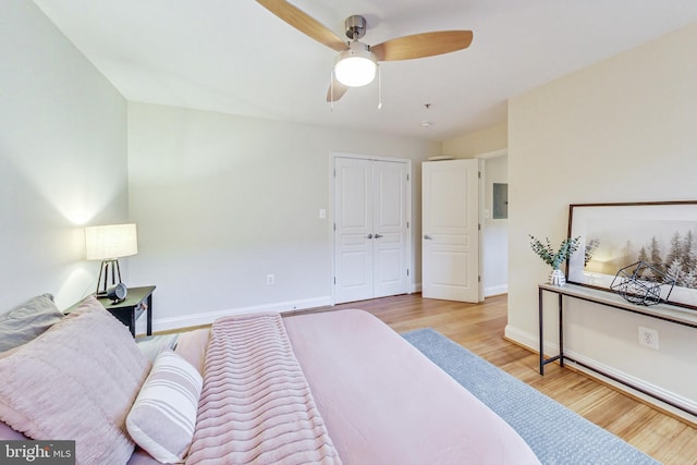 bedroom with ceiling fan, light hardwood / wood-style floors, electric panel, and a closet