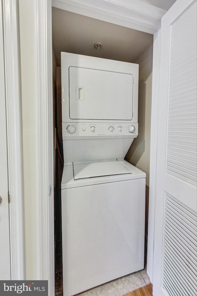 clothes washing area featuring light hardwood / wood-style flooring and stacked washer / drying machine