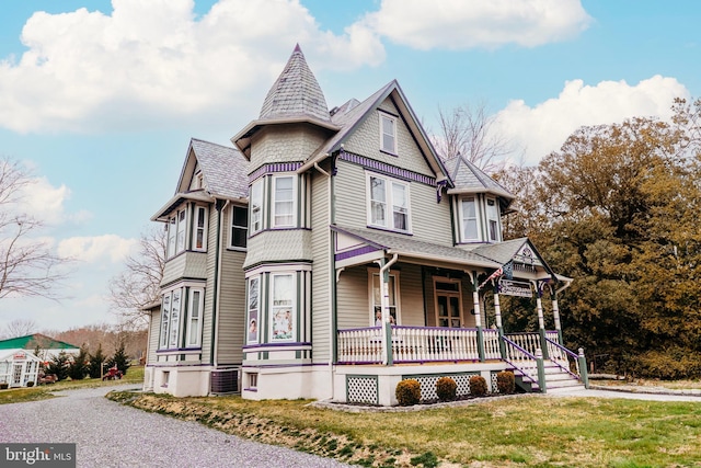 victorian house featuring covered porch, cooling unit, and a front yard