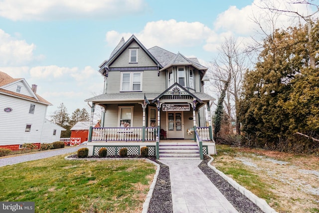 victorian house with a porch and a front lawn