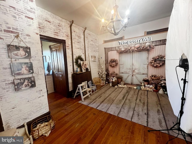 misc room with brick wall, a notable chandelier, and dark hardwood / wood-style floors