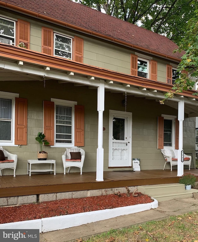 multi unit property with covered porch and a shingled roof