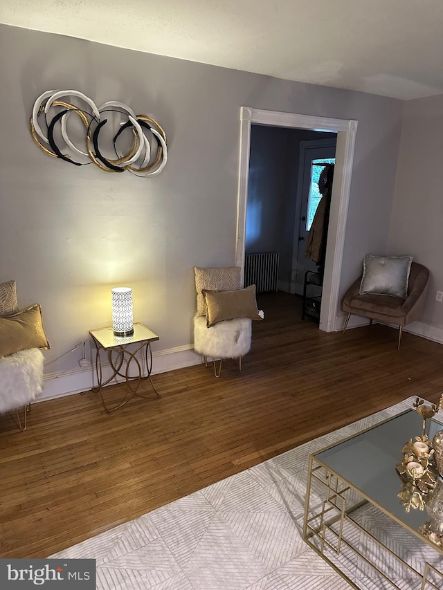 sitting room featuring radiator heating unit and hardwood / wood-style flooring